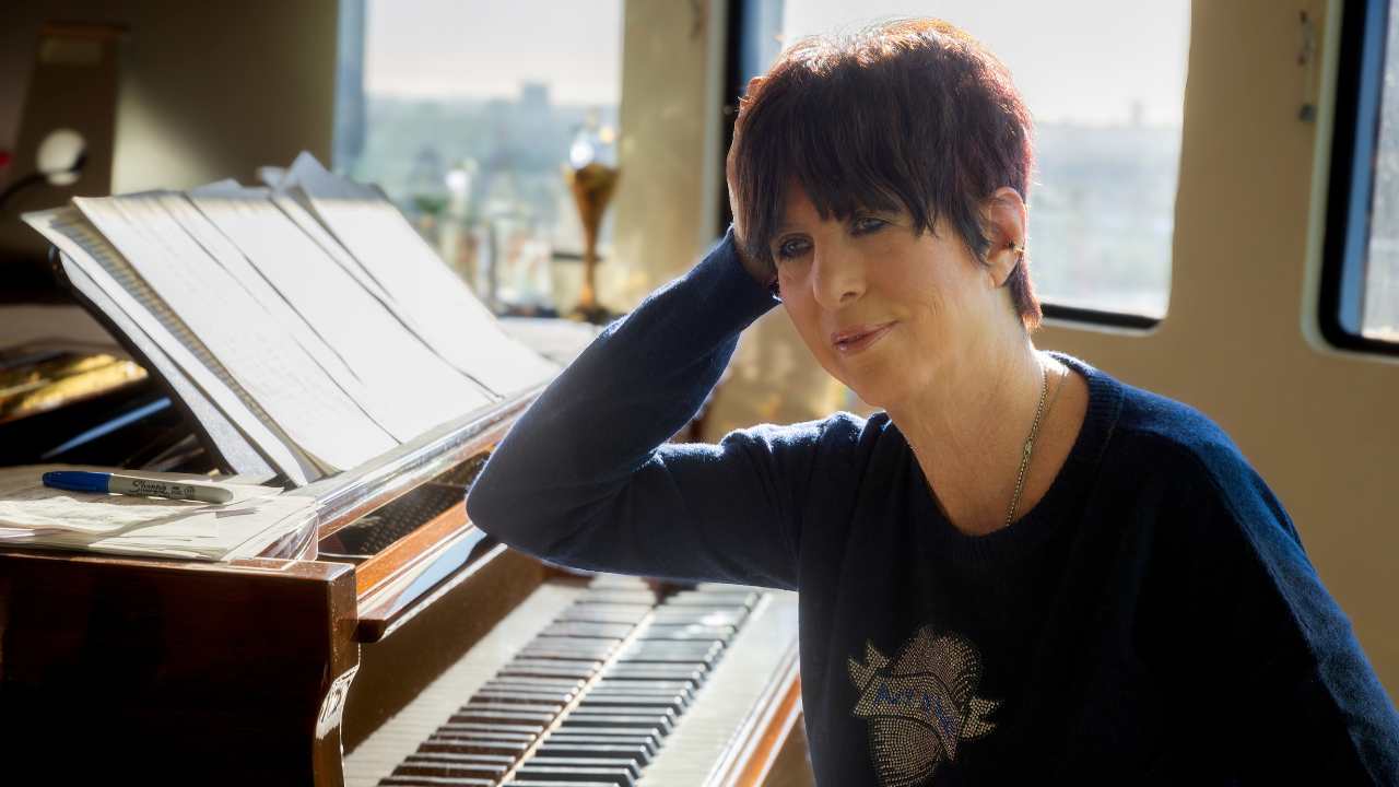 Diane Warren leaning on a piano